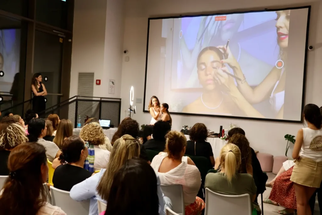 Professional makeup artist demonstrating where to apply face highlighter during a live beauty masterclass.